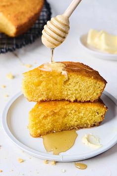 a piece of cake on a plate being drizzled with honey