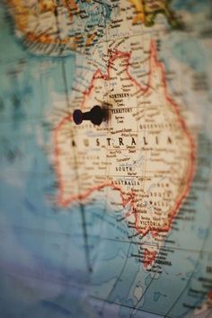 a close up view of australia on a globe with a black push pin in the middle