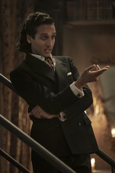 a man in a suit and tie is standing on the stairs with his hands out