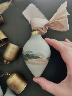 a hand holding an ornament in front of some thread spools