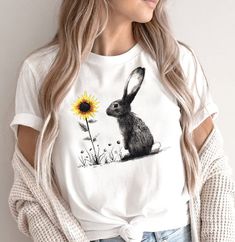 Introducing our delightful "Rabbit and Sunflower" T-shirt, where charm meets simplicity in a single design. This tee features an adorable illustration of a cute rabbit alongside a radiant sunflower, evoking a sense of whimsy and warmth. Crafted with premium-quality fabric and attention to detail, this tee isn't just clothing; it's a wearable piece of art that captures the essence of a sunny day in the countryside. The endearing illustration showcases the beauty of nature and the innocence of chi Bunny Nature, Bunny T Shirt, Sunflower Shirt, Cute Easter Bunny, Bunny Lovers, Bunny Shirt, Gardening Shirts, Cute Rabbit, Easter Shirt