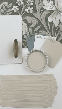 some paint samples are sitting on a table next to a wall paper and a painting brush