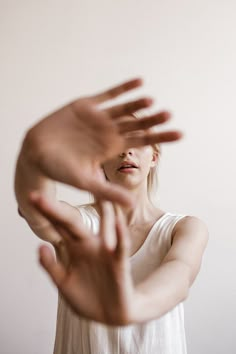 a woman holding her hands up in front of her face with both hands extended out