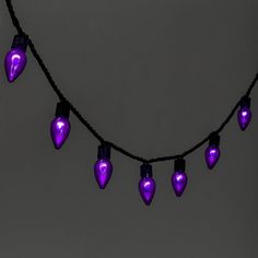 purple christmas lights are hanging on a black string