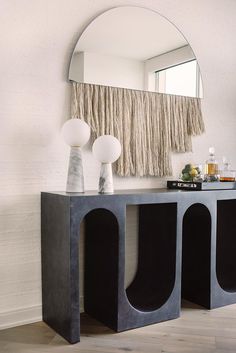 a console table with two lamps and a mirror on the wall in front of it