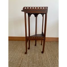 a small wooden table sitting on top of a carpeted floor next to a wall