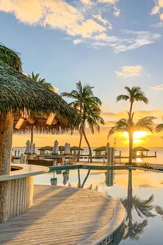 the sun is setting over an empty swimming pool with palm trees in the foreground