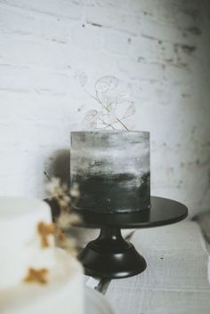 a white and black cake sitting on top of a wooden table next to a brick wall