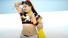 a woman in a colorful top and skirt with jewelry on her head is posing for the camera