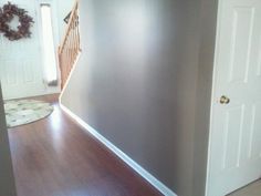 an empty room with wood floors and a door leading to the second floor, which has a wreath on the wall