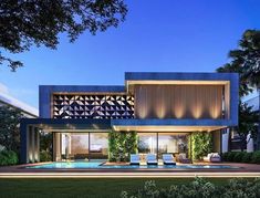 a modern house with an outdoor pool and lounge chairs in the front yard at night