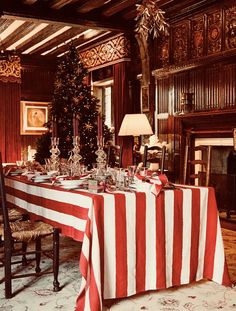 a dining room with a christmas tree in the corner and decorations on the table top