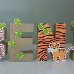 the letters are made out of cardboard and decorated with paper animals, leaves, and flowers