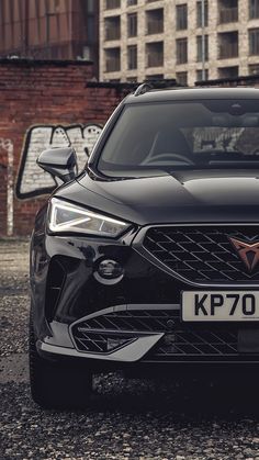 a black car parked in front of a building with graffiti on the side of it