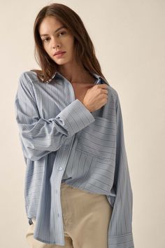 Striped button-down shirt. Collared neckline. Button front closure. Long raglan sleeves with buttoned cuffs. Chest pocket. Yoke back. Curved shirttail hem. Oversized fit. 100% Polyester. Imported. Designed in LA. Model wears size S. Blue Button-up Blouse For Everyday, Everyday Blue Button-up Blouse, Blue Shirt With Roll-up Sleeves And Shirttail Hem, Light Blue Button-up Shirt With Placket, Everyday Long Sleeve Blouse With Rolled Sleeves, Everyday Blue Blouse With Pockets, Light Blue Button-up Shirt With Pockets, Blue Shirt With Button Cuffs And Shirttail Hem, Light Blue Relaxed Fit Shirt For Fall