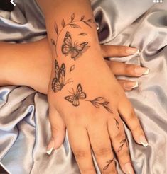 a woman's hand with tattoos on it and butterflies flying around the wrist area