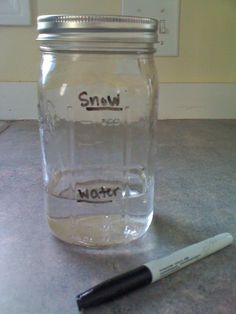 a glass jar with writing on it next to a marker