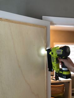 a person using a power drill to attach a piece of plywood on the wall