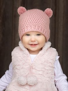 a baby wearing a pink knitted hat and vest