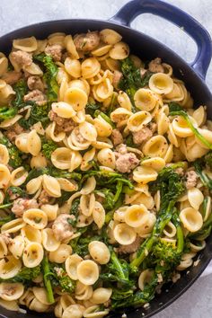 a skillet filled with pasta, sausage and broccoli