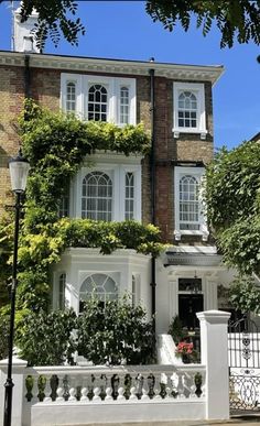 a large white house with lots of windows and plants on the side of it's wall