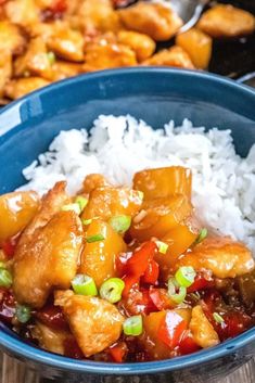 a blue bowl filled with rice and chicken on top of a wooden table next to other food