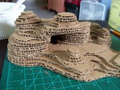 a close up of a model of a castle made out of brown paper on a green cutting board