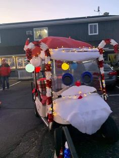 a golf cart decorated for christmas with lights and decorations on the front, parked in a parking lot