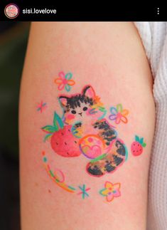 a small tattoo on the arm of a girl with a cat and two strawberrys