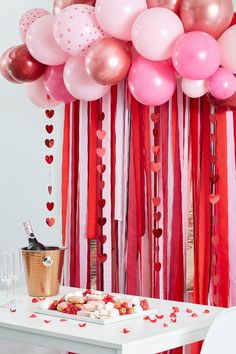 a table topped with lots of pink and red balloons