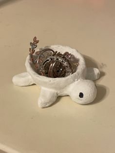 a small white turtle figurine with coins in it's shell