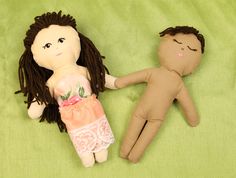 two dolls laying on top of a green blanket next to each other, one holding the hand of another doll