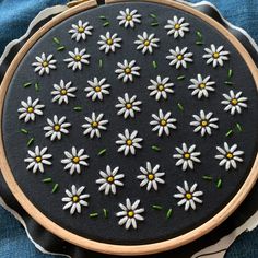 a close up of a embroidery on a piece of cloth with white and yellow daisies