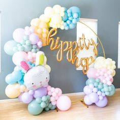 a balloon arch that says happy birthday with balloons around it and a bunny in the center