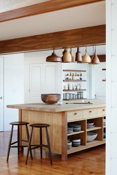 an island in the middle of a kitchen with two stools and plates on it