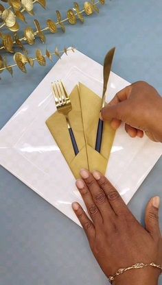 a person cutting up some paper on top of a white plate with gold forks and knives