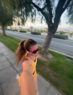 a woman wearing sunglasses is walking down the sidewalk