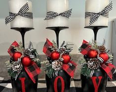 three black vases with red and white decorations on them sitting on a checkered table