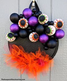 a halloween wreath made out of black, purple and orange decorations