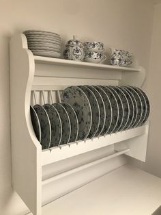 a white shelf filled with plates and cups on top of it's side rail