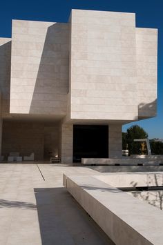 the exterior of a modern building with white walls and concrete steps leading up to it