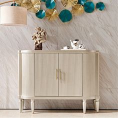 a white cabinet sitting in front of a wall with gold leaf decorations on top of it