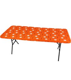 an orange table cover with white flowers on it and black legs, sitting against a white background