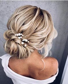 the back of a woman's head with blonde hair and pearls in her hair