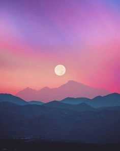 the sun is setting over some mountains with pink and purple clouds in the sky above