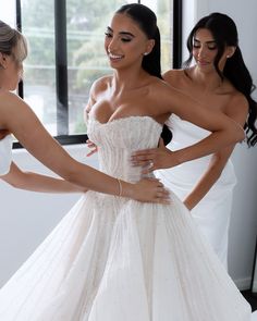 two beautiful women in white dresses standing next to each other