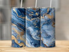 three blue, gold and white marbled metal tumblers with straws in them