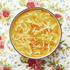 a bowl of chicken noodle soup on a floral tablecloth