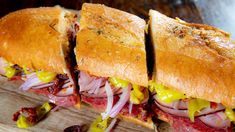 two sandwiches cut in half sitting on top of a cutting board with onions and meat