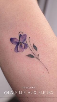 a purple flower on the back of a woman's arm